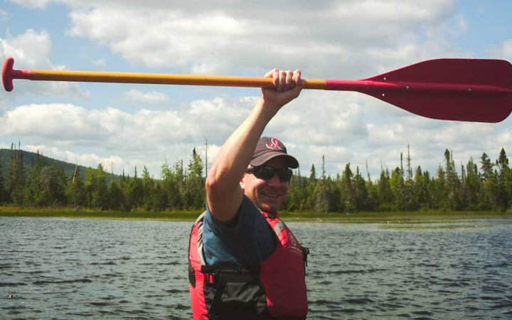 a veterans raises a paddle in the air on an outward bound expedition 